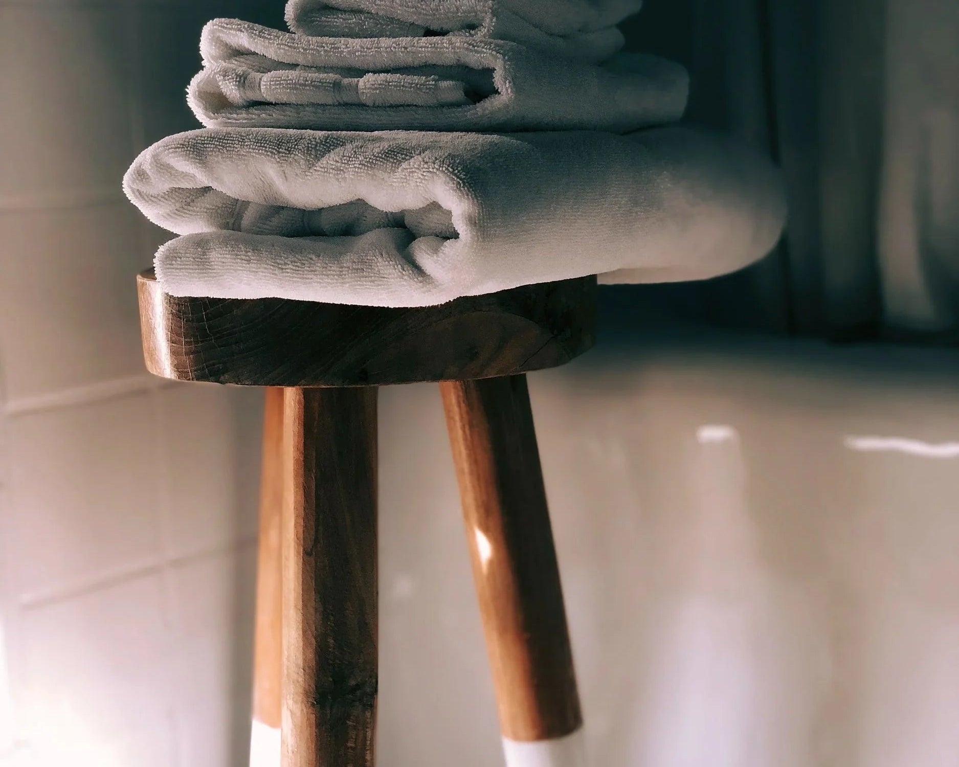 Serviettes blanches pliées empilées sur un tabouret en bois dans une salle de bain