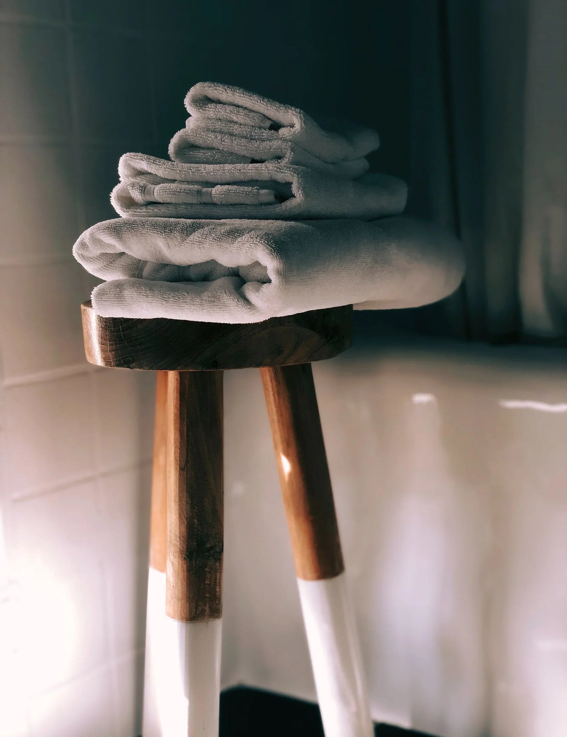 Serviettes blanches pliées empilées sur un tabouret en bois dans une salle de bain