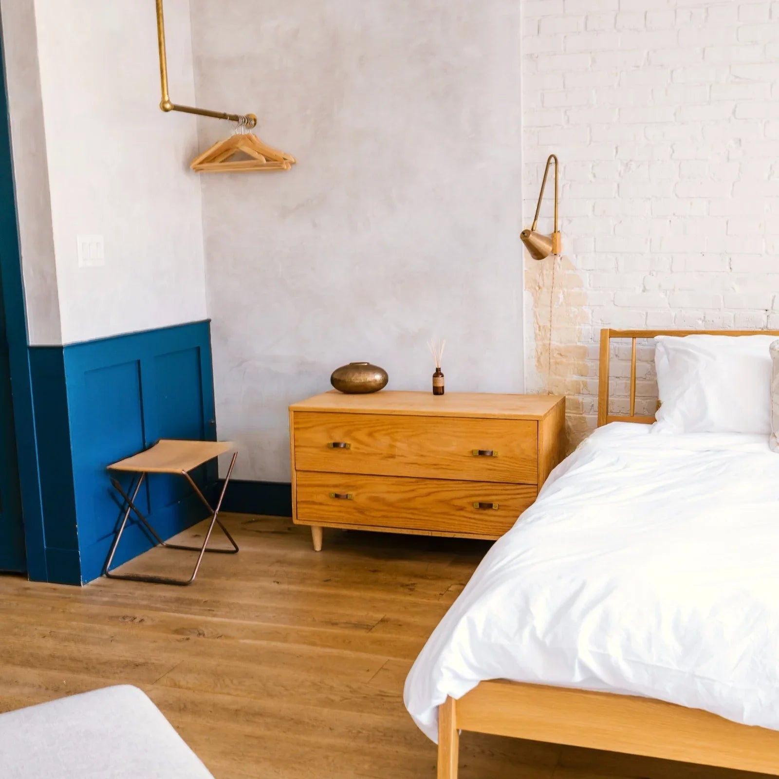 Chambre d'hôtel design avec linge blanc premium, meuble en bois et mur brique blanche