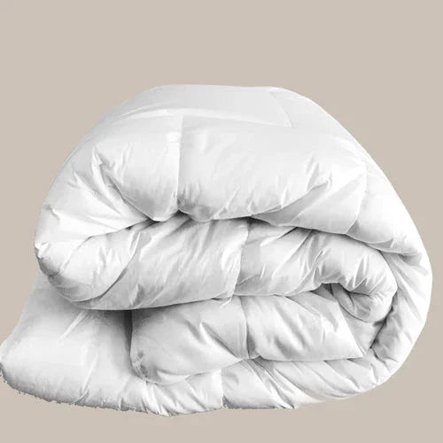 Couette blanche épaisse pliée sur fond beige, textile douillet et chaud