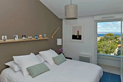 Chambre d'hôtel avec linge blanc premium et coussins décoratifs, vue sur mer, linge écoresponsable Oeko-Tex