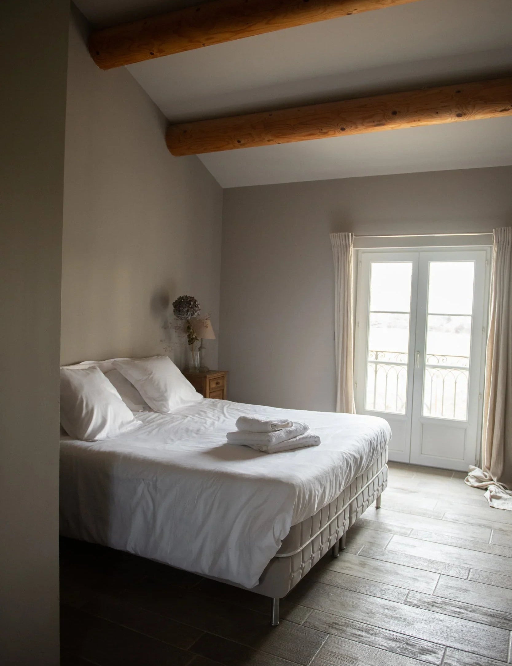 Chambre d'hôtel avec linge blanc premium, draps et serviettes écoresponsables Oeko-Tex, poutres en bois