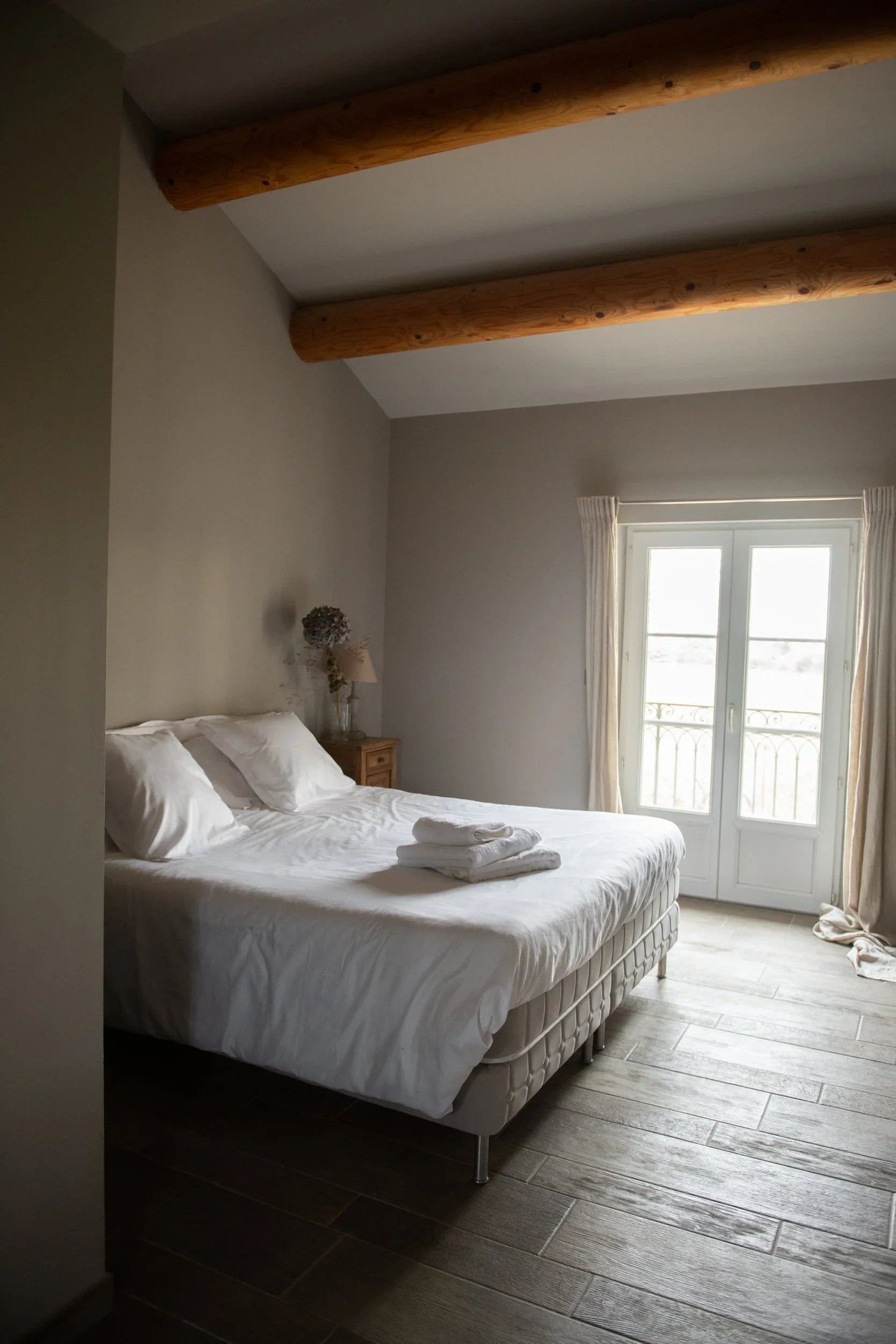 Chambre d'hôtel avec linge blanc premium, draps et serviettes écoresponsables Oeko-Tex, poutres en bois