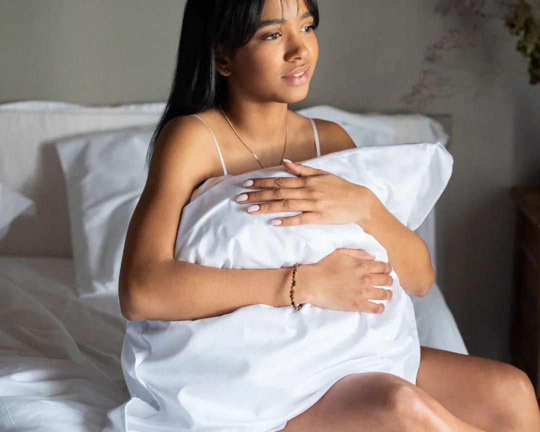 Femme dans un lit avec linge hôtelier blanc premium, draps et oreillers doux pour hôtel ou maison d'hôtes