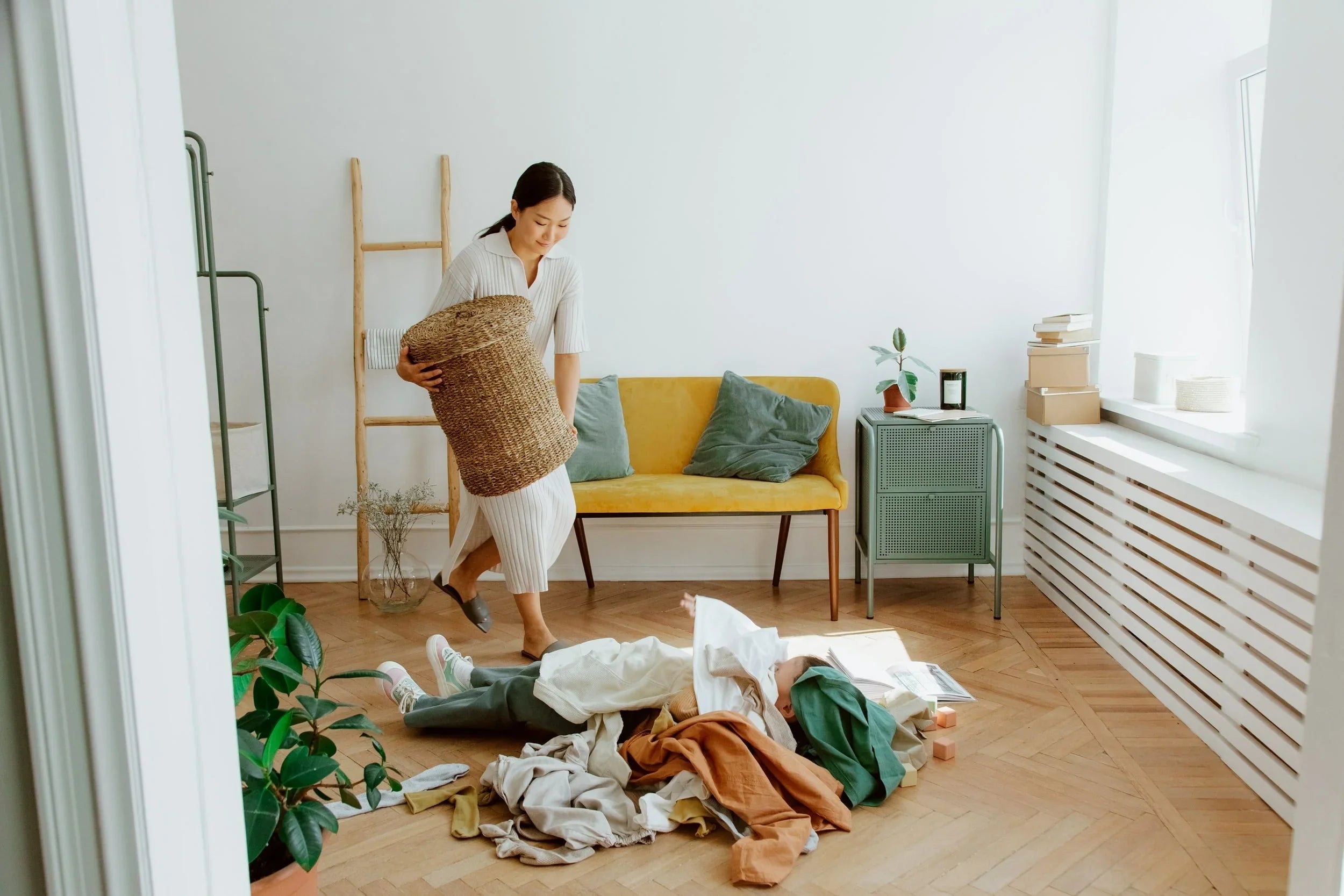 Femme organisant linge dans salon moderne avec canapé jaune et plantes