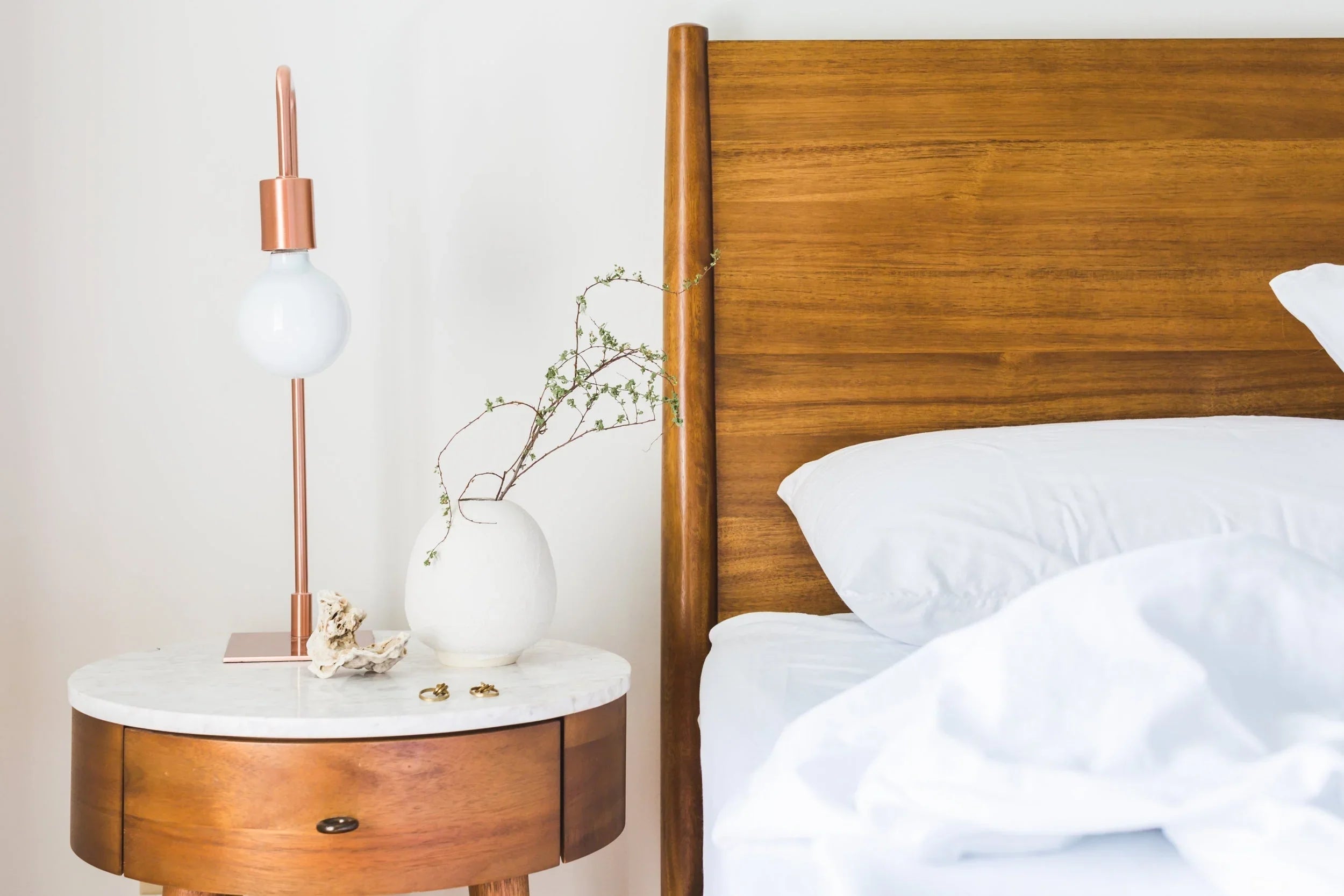 Linge hôtelier blanc premium sur lit avec tête de lit en bois et chevet design