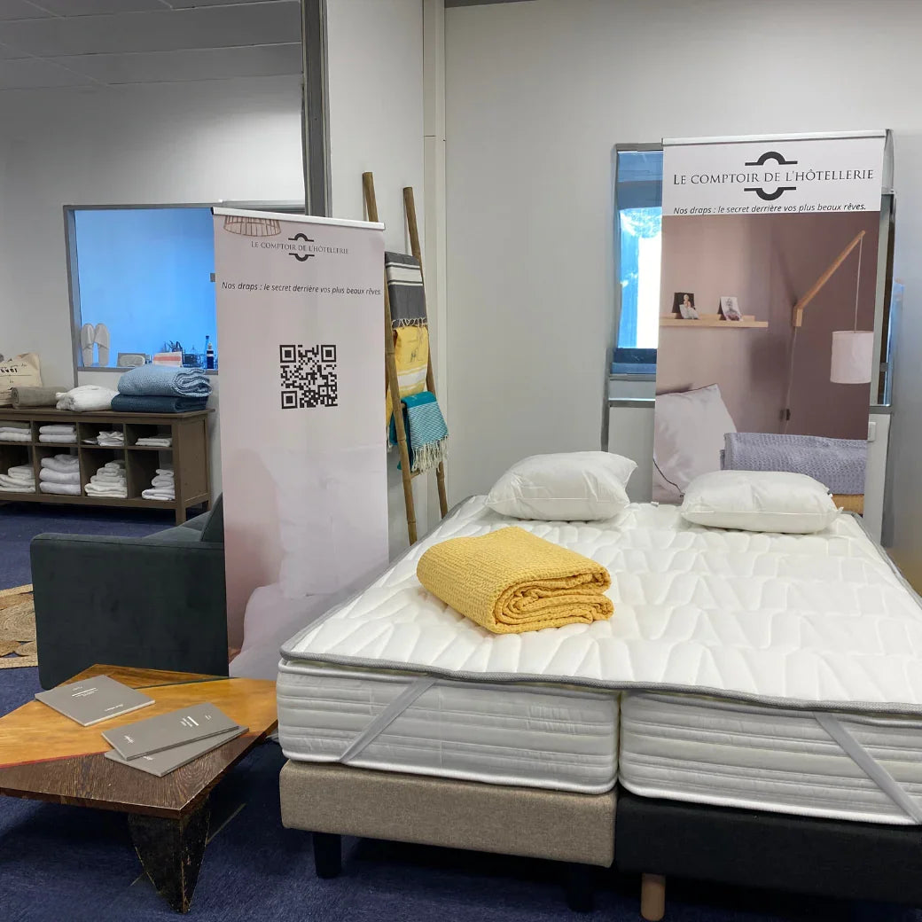 Showroom avec lit double, matelas, oreillers blancs et couverture jaune, décor minimaliste d'hôtel