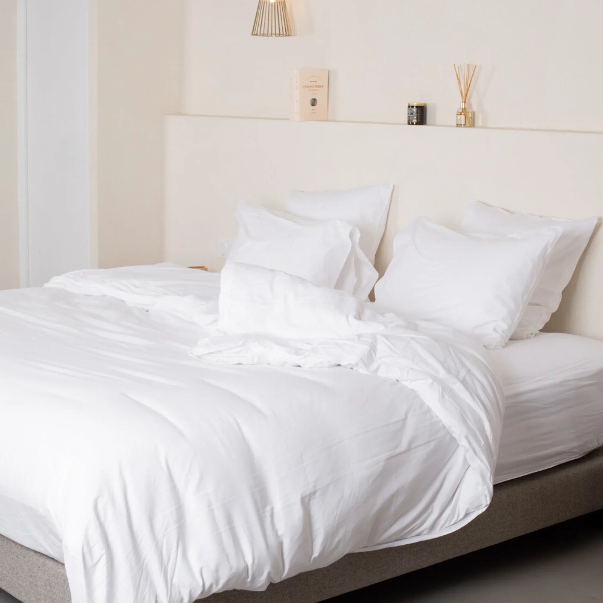 Lit moderne avec couette et oreillers en polycoton blanc, ambiance minimaliste et lumineuse