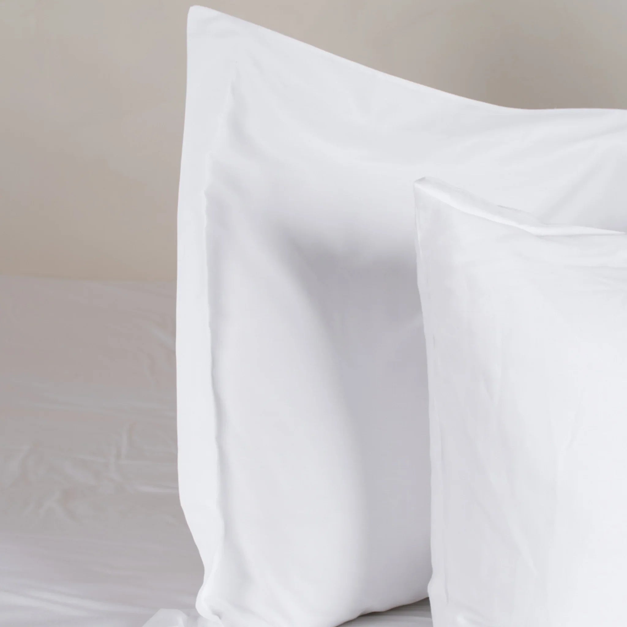 Taies d'oreiller satin coton blanc sur lit, ambiance chambre douce et épurée