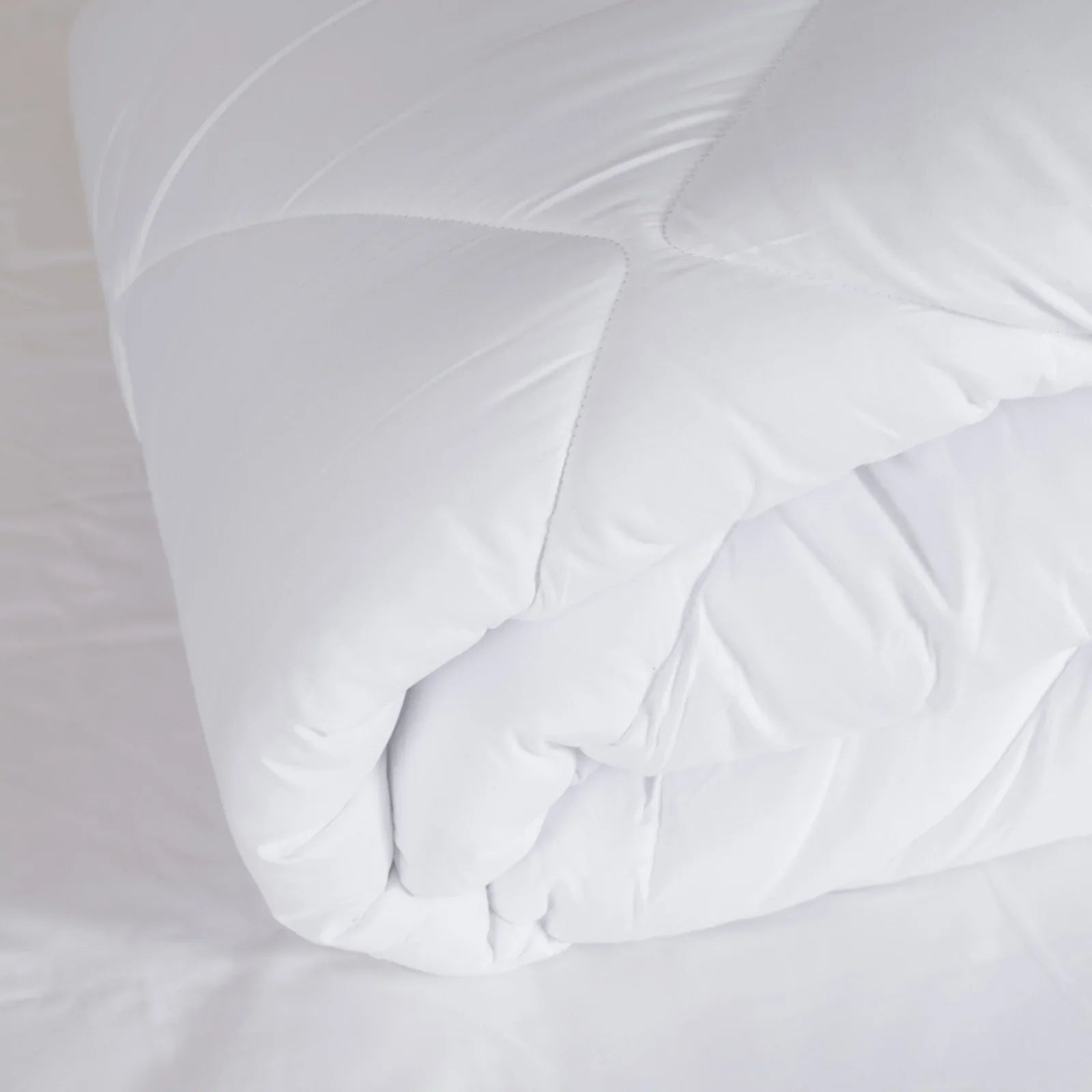 Couette blanche légère et moelleuse pliée sur un lit avec housse blanche