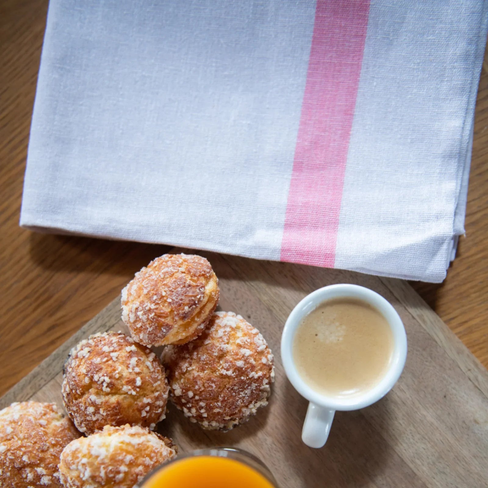 Torchon blanc à rayure rose avec chouquettes sucrées, tasse d'expresso et verre de jus d'orange